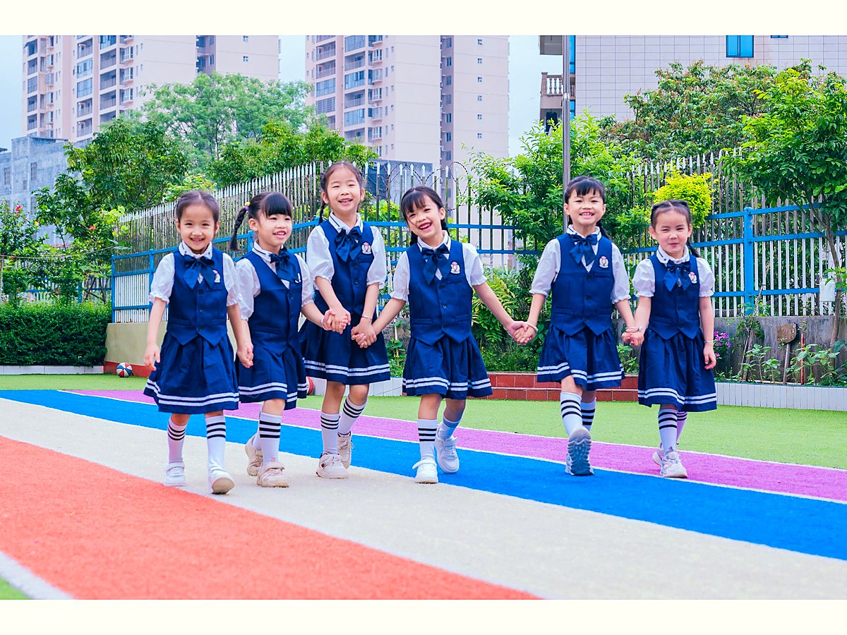 穿园服的小朋友牵手走在彩色跑道上